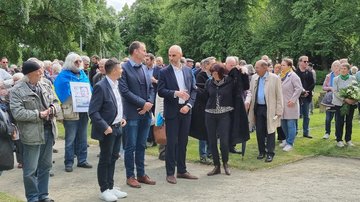 Zwei Männer unterhalten sich inmitten von vielen Gästen der Gedenfeier