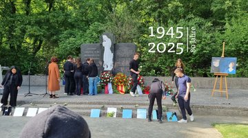 Jugendliche legen vor einem Ehrenmal Spiegel nieder